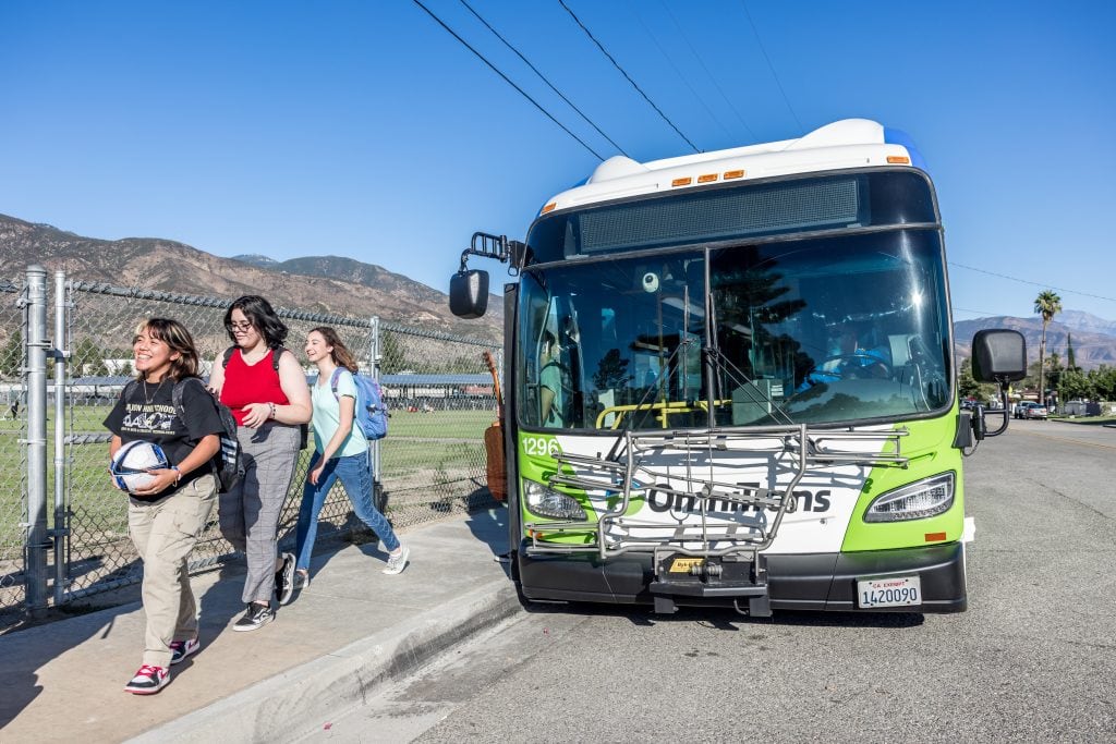 Students walking by Omnitrans bus